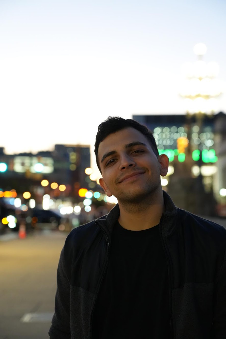Amirali outdoors at dusk with city lights in the background