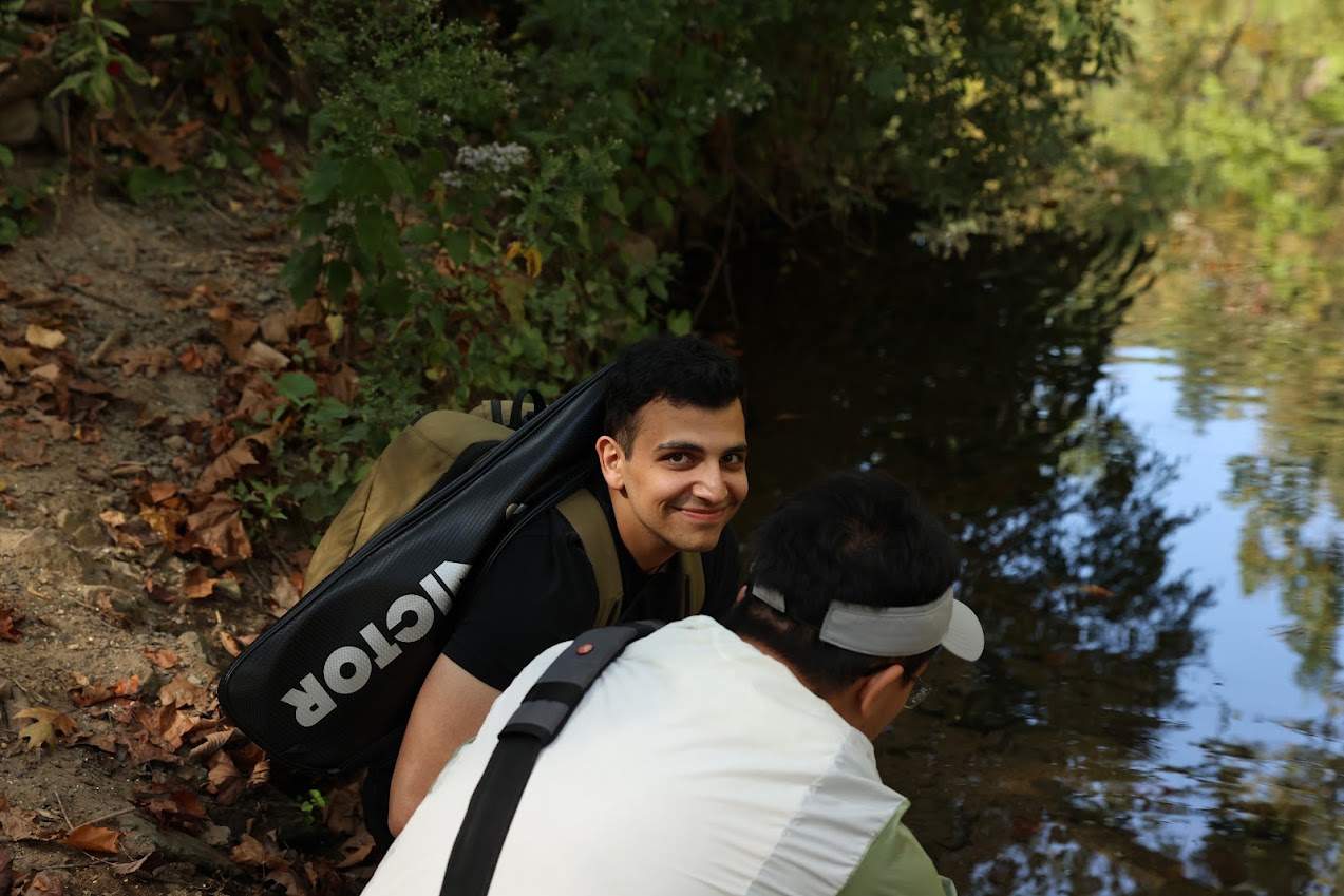 Amirali beside a wooded creek with a companion