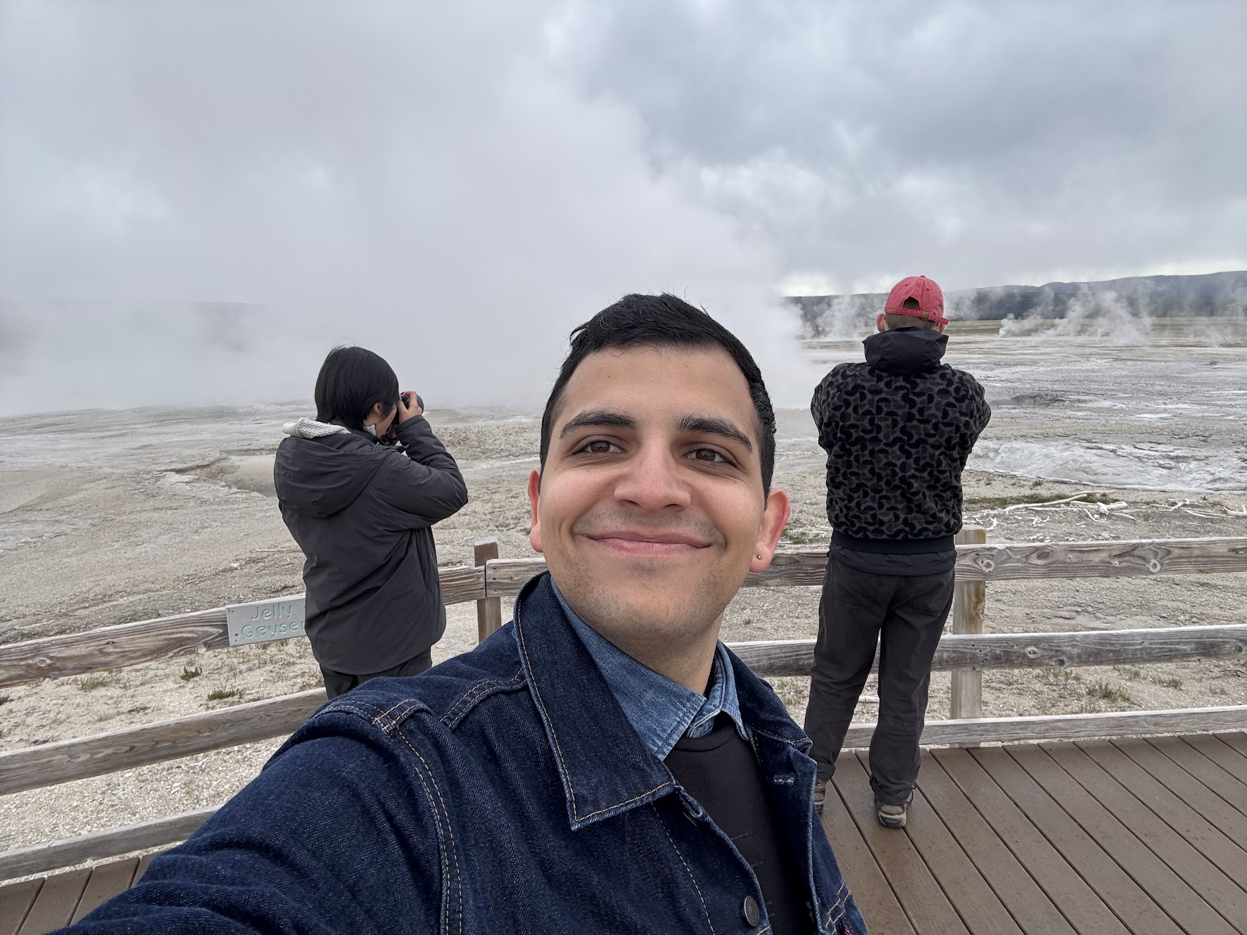 Amirali at Yellowstone, with geothermal steam and two companions in the background